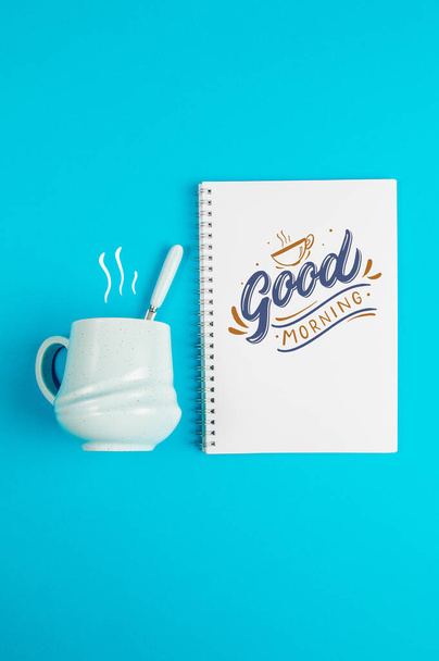 Blue coffee mug on a blue background with the text and a blank white page - Photo, Image