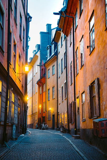 Scenic schemerzicht op traditionele huizen in een prachtige steeg in Stockholm 's historische Gamla Stan (Old Town) verlicht tijdens het blauwe uur in de schemering, het centrum van Stockholm, Zweden - Foto, afbeelding