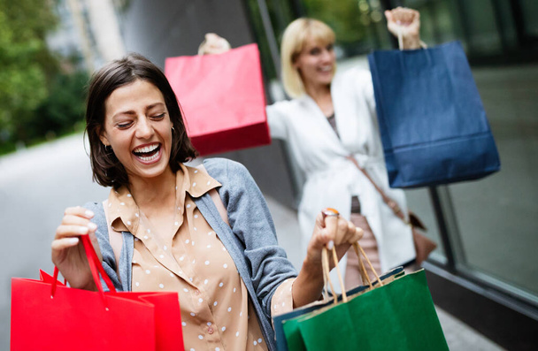 Beautiful happy girls with shopping bags walking at the mall and having fun - Valokuva, kuva