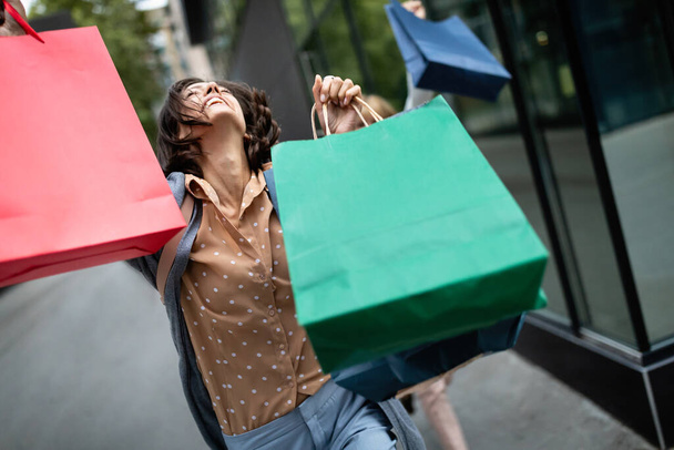 ショッピングで楽しむショッピングバッグと幸せな女性。消費主義、ショッピング、旅行、ライフスタイルの概念 - 写真・画像