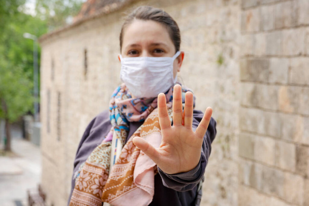 Blisko kobiety w masce ochronnej twarzy, przygotuj się na Coronavirus i pm 2.5 walki i pokazać stop gestem ręce zatrzymać wirusa korony zewnątrz obok drogi w tle. - Zdjęcie, obraz