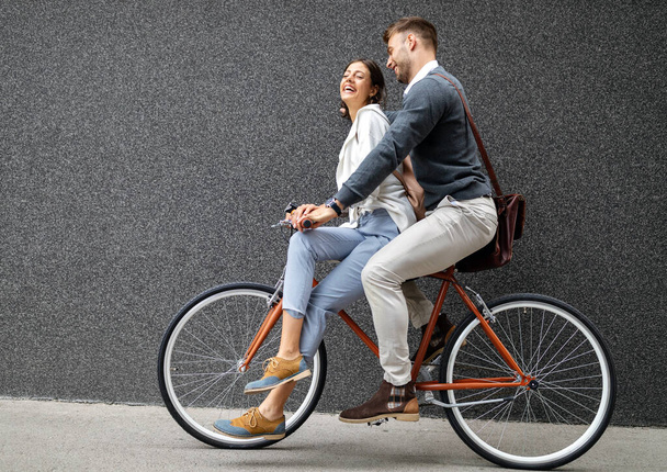 Beautiful happy young couple in love on bicycle in the city having fun - Fotó, kép