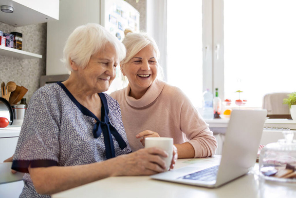 Adult daughter teaching her elderly mother to use laptop - Foto, Imagem