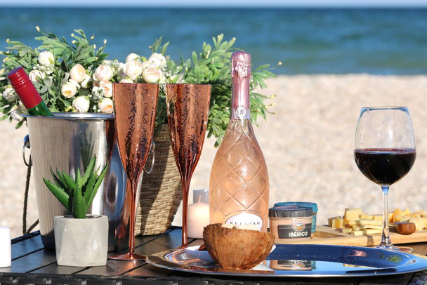 Vinné sklenice s růžovým vínem a květiny s jídlem na stole - Fotografie, Obrázek