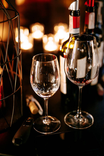 Zwei leere Becher unterschiedlicher Größe bereiten sich auf die Weinprobe im modernen Restaurant vor. Gemütliche dunkle Atmosphäre mit Kerzenschein. Hintergrund verschwimmen. - Foto, Bild