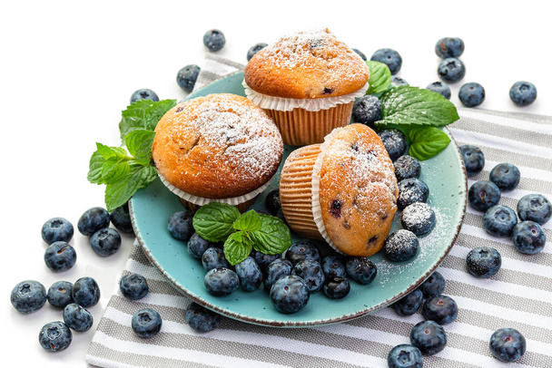 Muffins de mirtilo e mirtilos frescos em uma chapa azul
 - Foto, Imagem