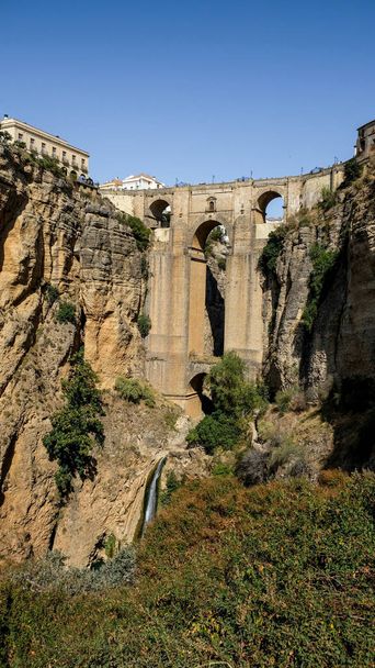Puente Nuevo famous new bridge with archs in the heart of old village Ronda in Andalusia, Spain. Touristic landmark on a sunny day with buildings in the background. View from below. - Photo, Image
