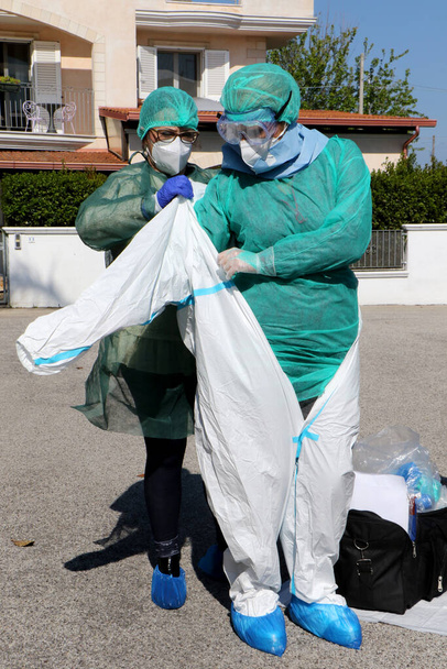 Italiaanse verpleegkundigen bereiden zich voor met beschermende kleding, beschermende maskers en handschoenen om thuis een uitstrijkje te maken voor een mogelijk geval van coronavirus covid-19 in Puglia, Italië - 24 / 04 / 2020 - Foto, afbeelding