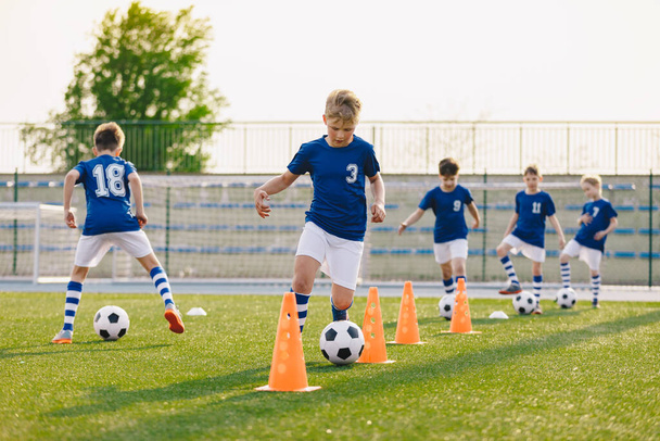 サッカートレーニング-ウォームアップとスラロームドリル。草の学校フィールドでヨーロッパサッカーを練習している男の子 - 写真・画像