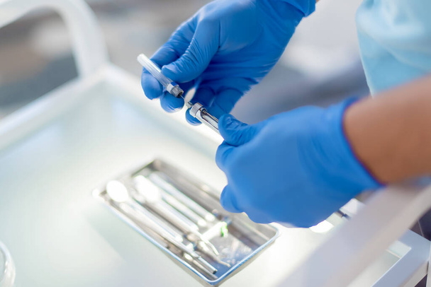 Dentist holding in his dentist's hands ib blue gloves carpool syringe for local anesthesia on white background isolated - Foto, afbeelding