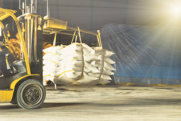Chariot élévateur transporte jumbo sac de sucre blanc raffiné pour mettre sur la pile à l'intérieur de l'entrepôt. Opérations et gestion des entrepôts de sucre
. - Photo, image