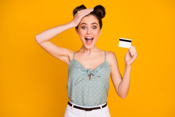 Portrait of astonished crazy girl get vip credit card impressed she can buy many purchases touch hand head scream wow omg wear tank top isolated over shine color background - Photo, Image