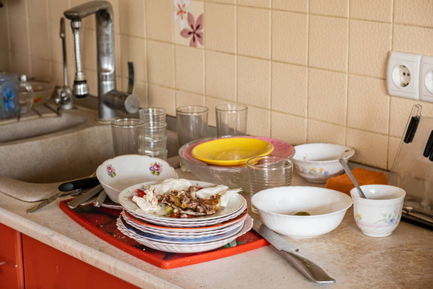 Muchos platos sucios cerca del fregadero en la encimera. Placas con sobras en la cocina de la casa
. - Foto, Imagen
