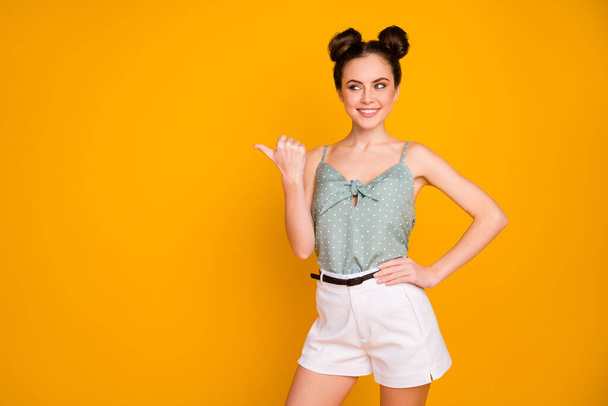 Portrait of positive cheerful girl promoter point thumb copyspace indicate ads promotion recommend suggest select wear style singlet isolated over bright shine color background - 写真・画像