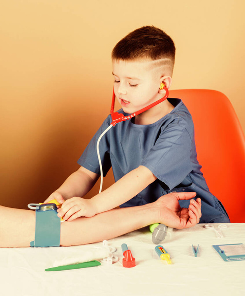 Medical examination. Medical education. Boy cute child future doctor career. Health care. Kid little doctor sit table with stethoscope and medical tools. Medicine concept. Measuring blood pressure - Фото, зображення