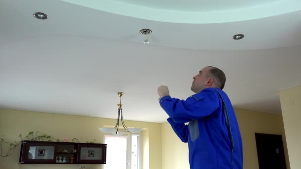 worker man change LED light bulb in ceiling in client room. 4K - Footage, Video