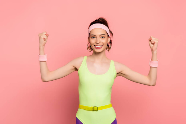 cheerful sportswoman with clenched fists looking at camera on pink  - Фото, изображение
