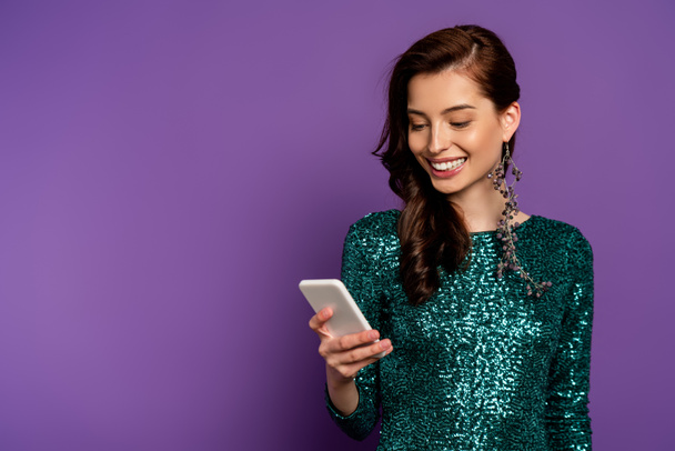 happy young woman looking at smartphone on purple  - Zdjęcie, obraz