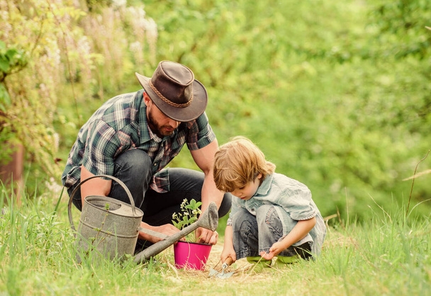 Little helper in garden. Make planet greener. Growing plants. Take care of plants. Day of earth. Boy and father in nature. Gardening tools. Planting flowers. Dad teaching little son care plants - Φωτογραφία, εικόνα