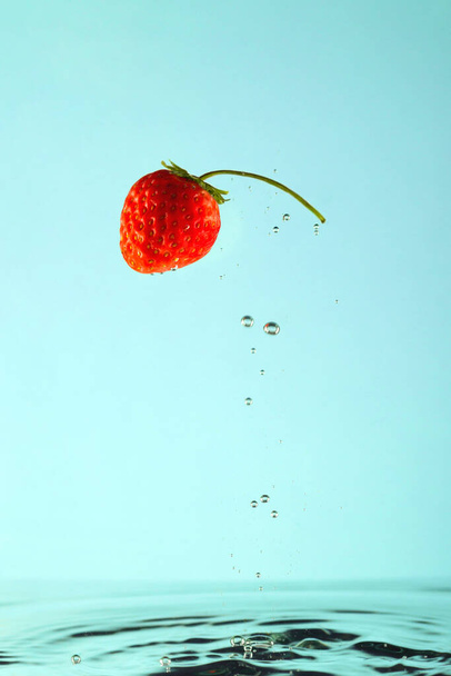Κόκκινη φράουλα με βολβούς σε καθαρό νερό. - Φωτογραφία, εικόνα