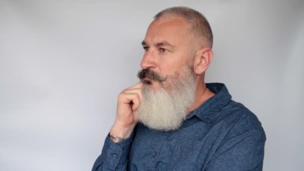 Arckép vonzó középkorú szakállas fehér férfi figyelmes vagy zaklatott. Szürke háttér. - Felvétel, videó