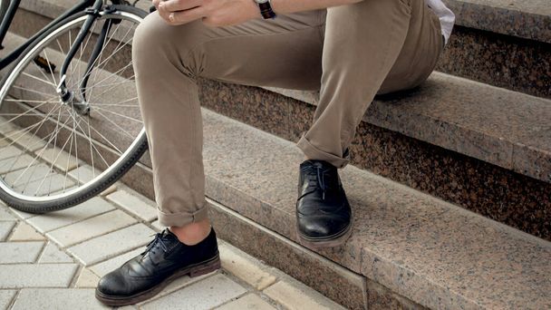 Male feet and vintage bicycle on stone stairs on city street - Photo, image