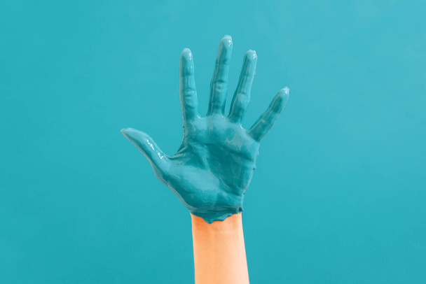 Kobieca ręka z bliska w niebieskiej farbie na niebieskim tle. Koncepcja naprawy.  - Zdjęcie, obraz