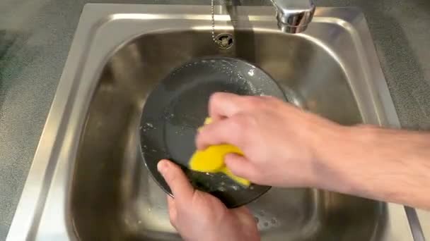 Mans kézmosás egy edényt egy súroló a konyhában mosogató. Közelkép, koncepciók, 4K - Felvétel, videó