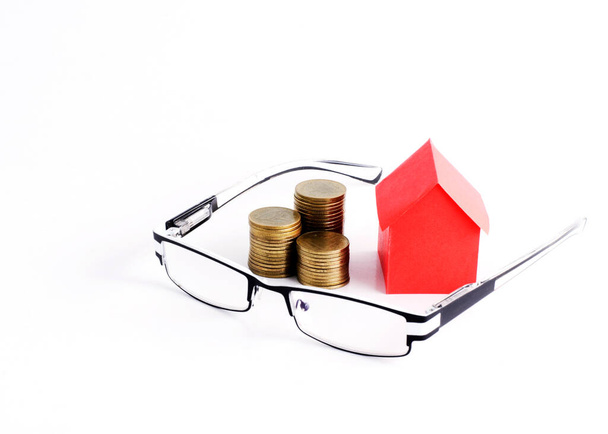 Червоний будинок папір і монети стек і окуляри на білому тлі - Фото, зображення