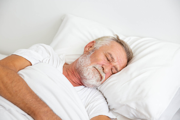 Worried senior retirement man lying awake in his bed - Foto, Imagen