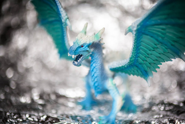 IJsblauwe draak speelgoed foto op wazig bokeh achtergrond, winter koele kleuren toon - Foto, afbeelding