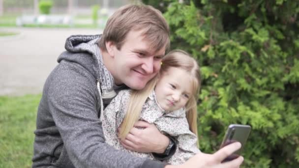 Papá toma una foto selfie en un teléfono móvil con una hermosa hijita
 - Imágenes, Vídeo
