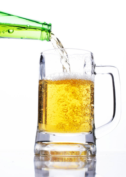 Comemore o conceito de dias de cerveja com o derramamento de cerveja em um copo no fundo branco
 - Foto, Imagem
