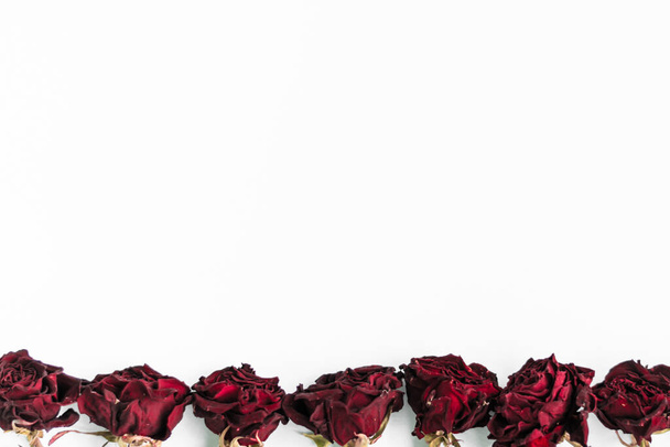 Beautiful red dry roses on a white background. Flat lay, top view, copy space. Flower arranging concept. Festive decor for greeting cards, websites and wedding invitations. - Foto, Imagem
