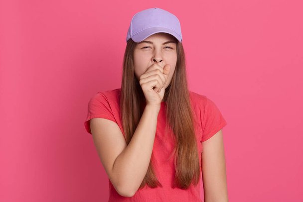 Portrait of young woman yawning. Tired female posing isolated over pink background, lady covering mouth with fist, looks sleepy, wearing casually, needs more time to rest. - Φωτογραφία, εικόνα
