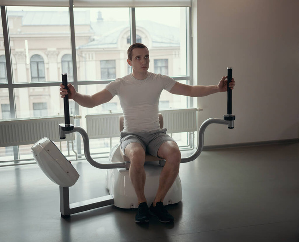 Nowoczesna siłownia - facet siedzący na maszynie do treningu siłowego - Zdjęcie, obraz