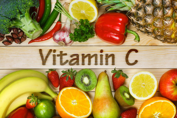 Vitamine C in groenten en fruit. Natuurlijke producten rijk aan vitamine C zoals sinaasappelen, citroenen, gedroogde vruchten roos, rode peper, kiwi, peterselie bladeren, knoflook, banaan, peer, appel, ananas, chili en broccoli. - Foto, afbeelding