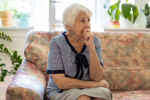Portret van een bejaarde vrouw die zich thuis zorgen maakt - Foto, afbeelding