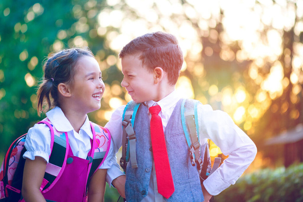 Two little schoolchildren are happy to meet again at the beginning of a new school year - Fotoğraf, Görsel
