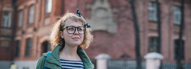 Портрет молодой женщины на европейской улице. Стильная блондинка в очках и полосатая рубашка для прогулки по старому городу в солнечный день
 - Фото, изображение
