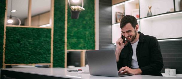 Um homem trabalha num portátil num escritório ou a trabalhar em equipa. Jovem empresário em roupas elegantes com um computador em um local de trabalho moderno. - Foto, Imagem