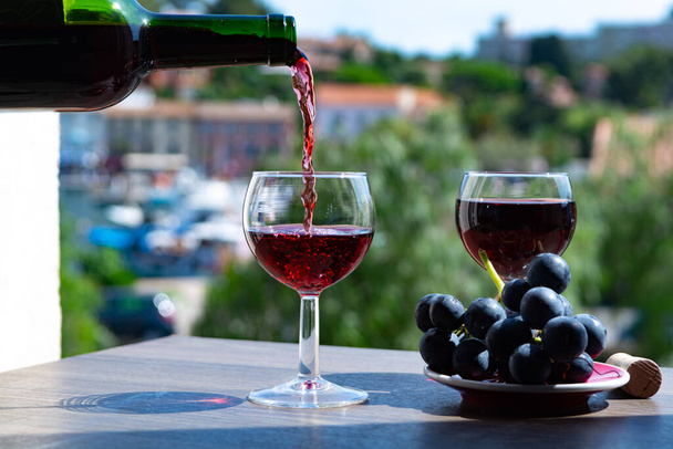 Офіціант поливає червоне вино на терасі кафе в сонячний літній день у Франції. - Фото, зображення