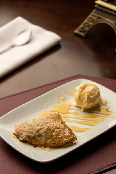 crepe with caramel dulce de leche filling and vanilla ice cream on wooden table - Foto, Bild
