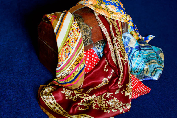 Старовинна дерев'яна скриня з стильними аксесуарами Індіанський та арабський шовкові носовички вишиті нитки, кольорові друкарські тканини зі східним орнаментом та дизайном. - Фото, зображення