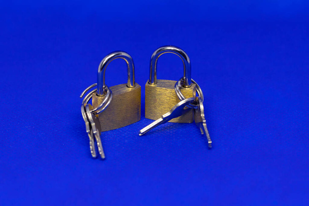 Dos candados pequeños con dos llaves. La foto tiene un fondo azul
 - Foto, Imagen