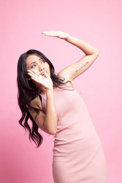 Excited young Asian woman look up on pink background - 写真・画像