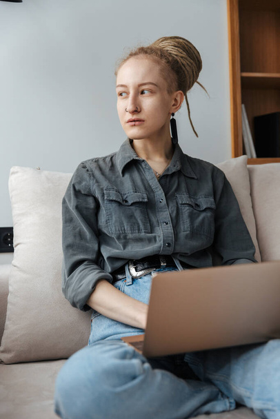 Image of a concentrated young girl with dreadlocks and piercing indoors using laptop computer. - Φωτογραφία, εικόνα