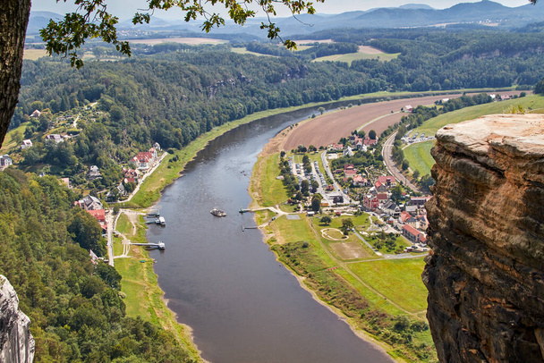 Näkymä Elben ja lauttasataman näkökulmasta Rathen maisemamuodossa joki, pienet talot, parkkipaikka ja lautta - Valokuva, kuva