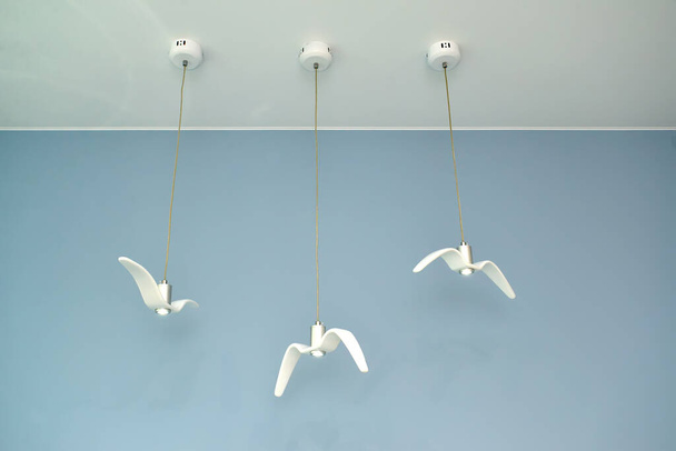 Three suspended ceiling lamps in the form of white gulls - Foto, afbeelding