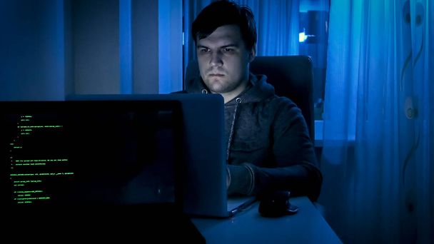 Portrait of male programmer or hacker working on computer at night - Photo, Image